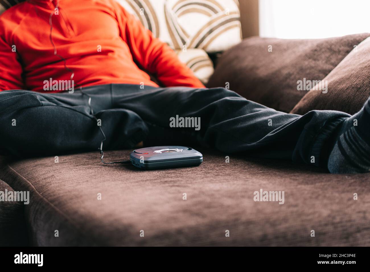 Unrecognizable man with headphones listening to music at home. Relaxed man listening to music on the sofa at home. Stock Photo