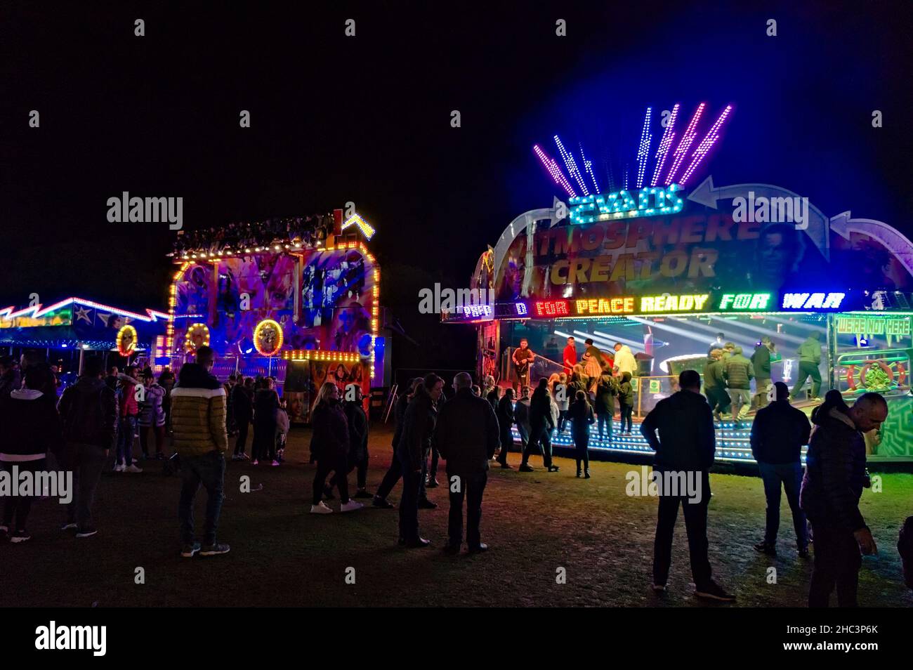people enjoying the arcades at the night time funfair in the park Stock Photo