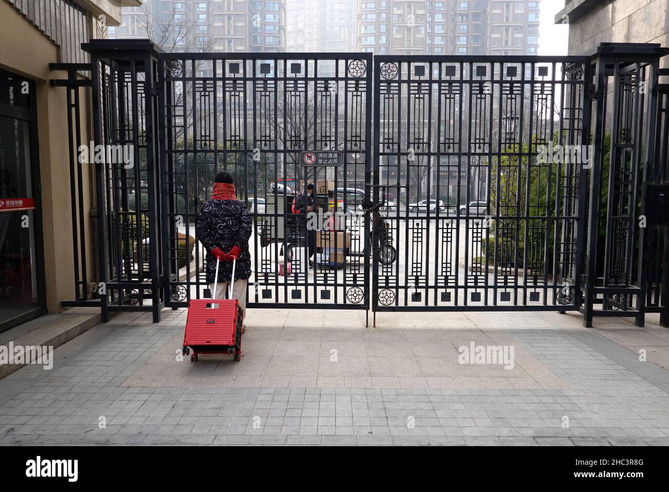 XI'AN, CHINA - DECEMBER 24, 2021 - A resident contacts an SF express Courier at the gate of a gated community in Xi 'an, Shaanxi province, Dec 24, 202 Stock Photo