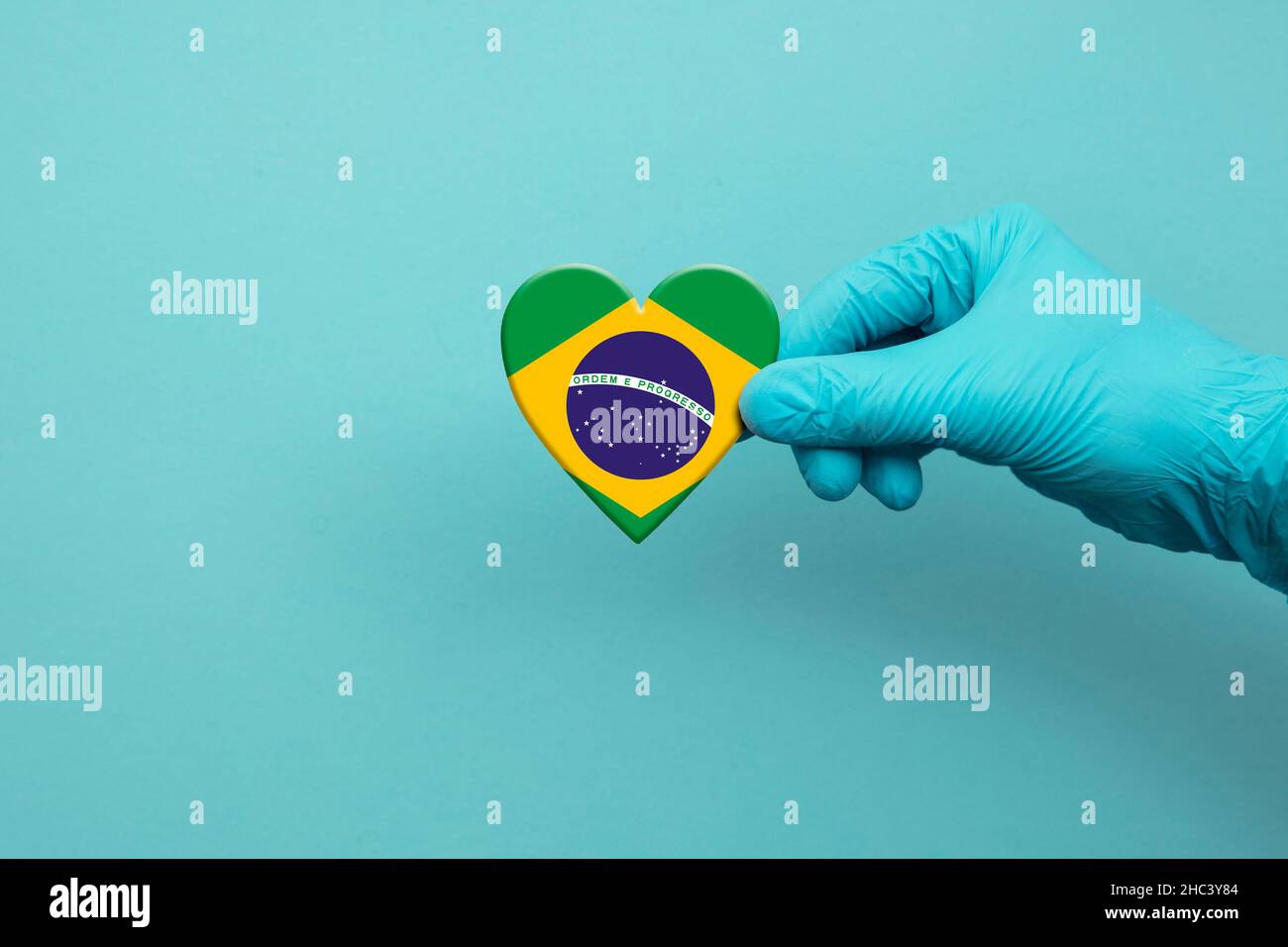 Medical workers hand wearing surgical glove holding Brazil flag heart