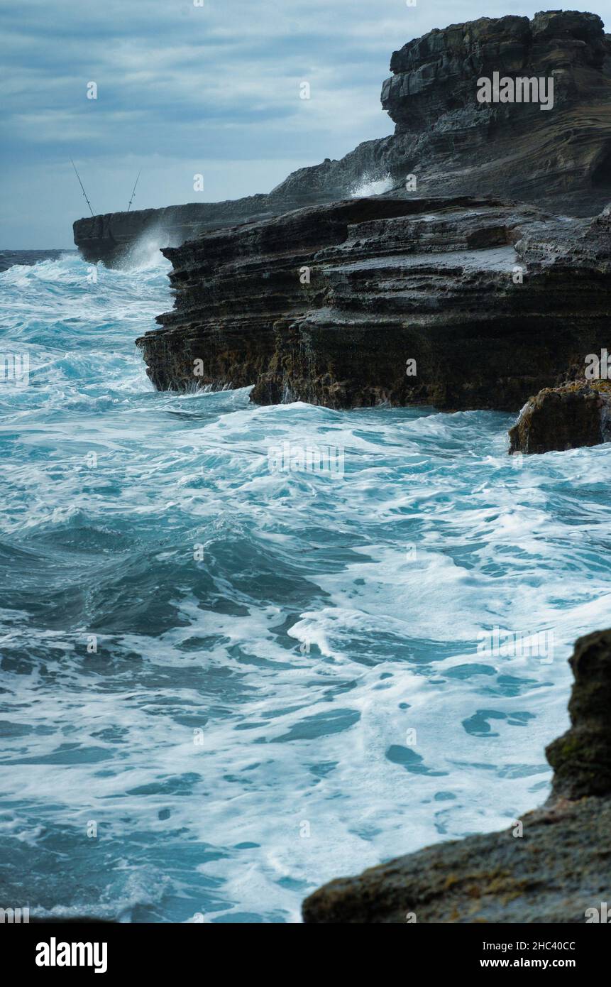 Vertical shot of blue sea waves splashing against rocks Stock Photo - Alamy