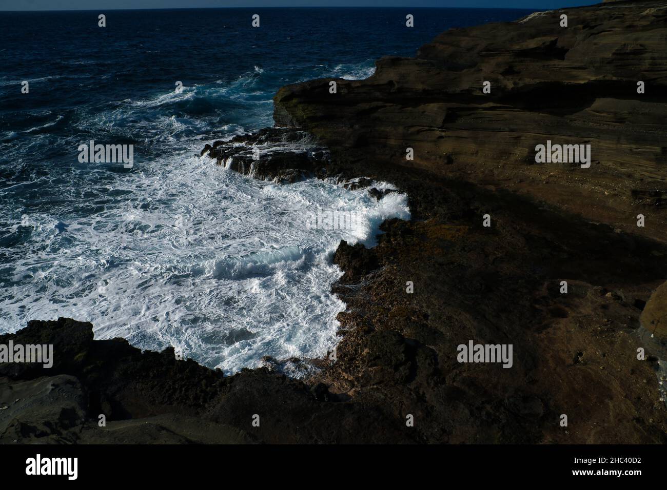 Aerial view of the blue sea waves splashing against rocks and cliffs ...