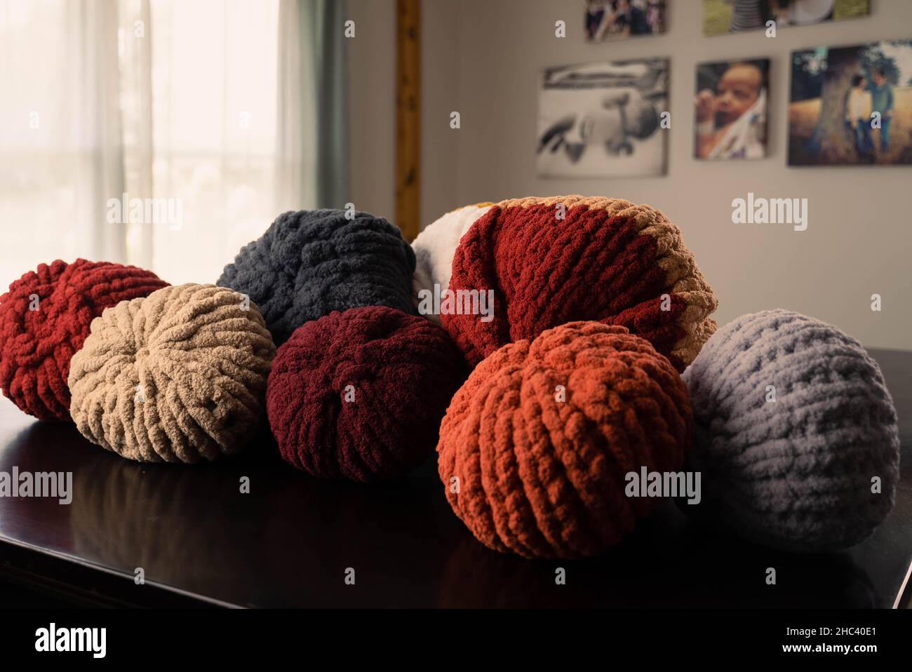 A closeup shot of colorful rolled up chunky handmade blankets on the table Stock Photo