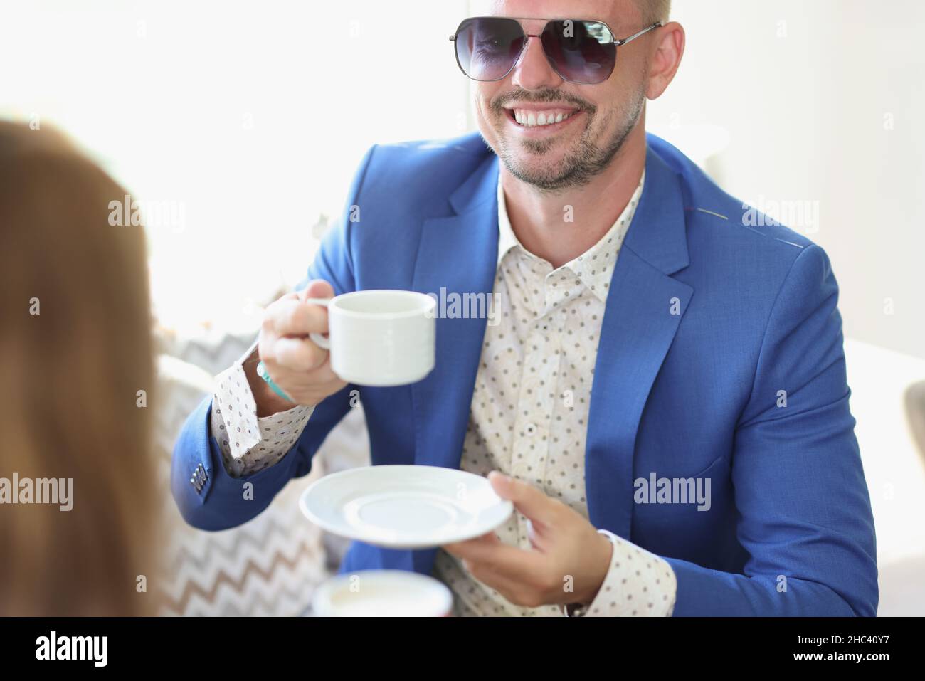 Well dressed smiling man drinking coffee in cafe on business meeting with partner Stock Photo