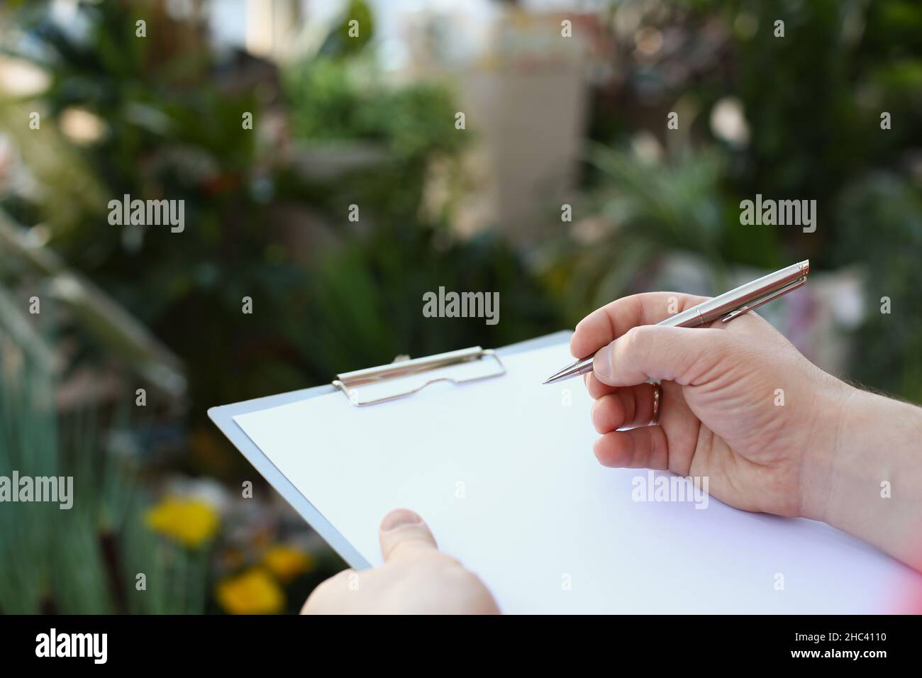 Human hand writing on clipboard with white paper, pen and blank ...
