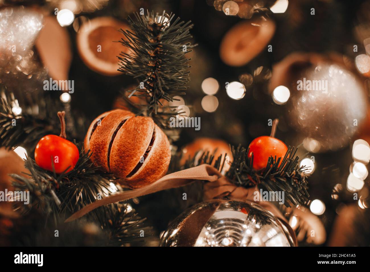 https://c8.alamy.com/comp/2HC41A5/christmas-tree-branches-decorated-with-dried-oranges-mandarins-and-cherry-cozy-details-and-golden-bokeh-garlands-lights-winter-magic-decorations-2HC41A5.jpg