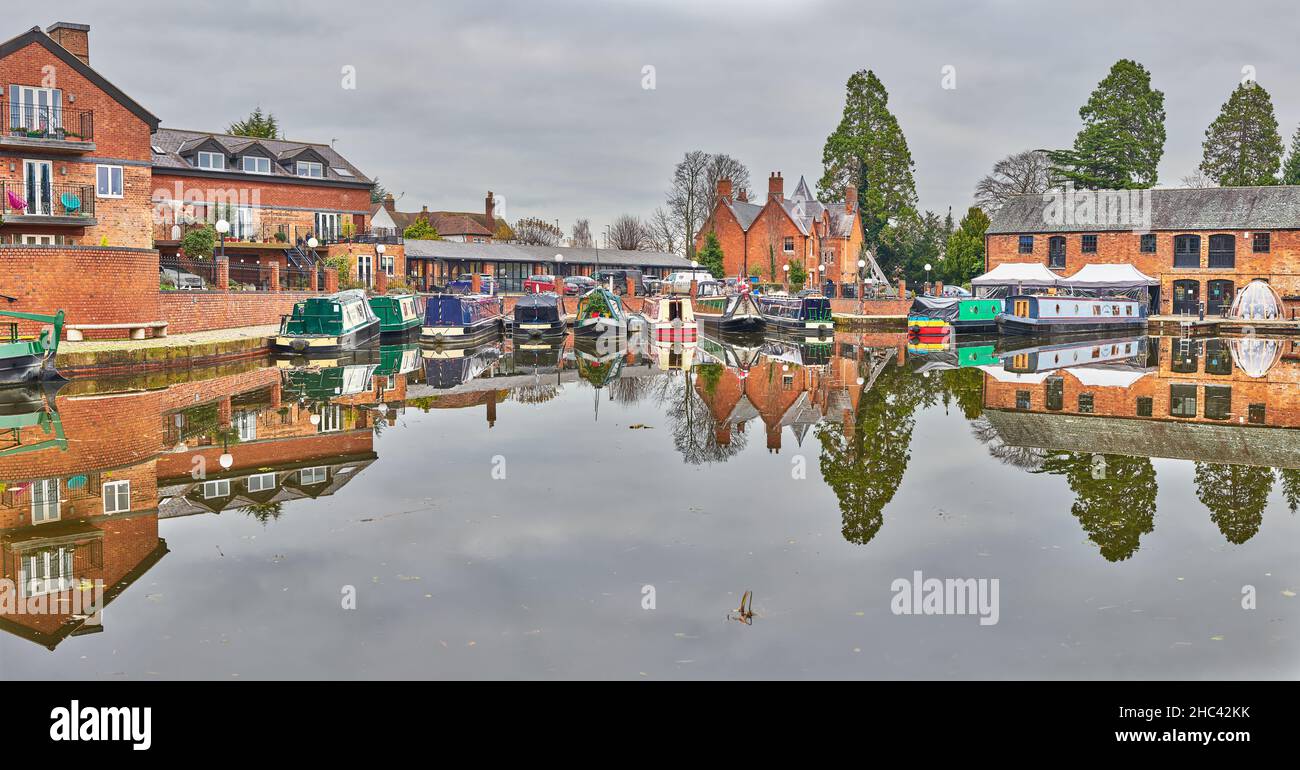 Narrow boats beside warehouses converted to flats and a restaurant at the Union Wharf basin of the Grand Union canal Market Harborough, England. Stock Photo