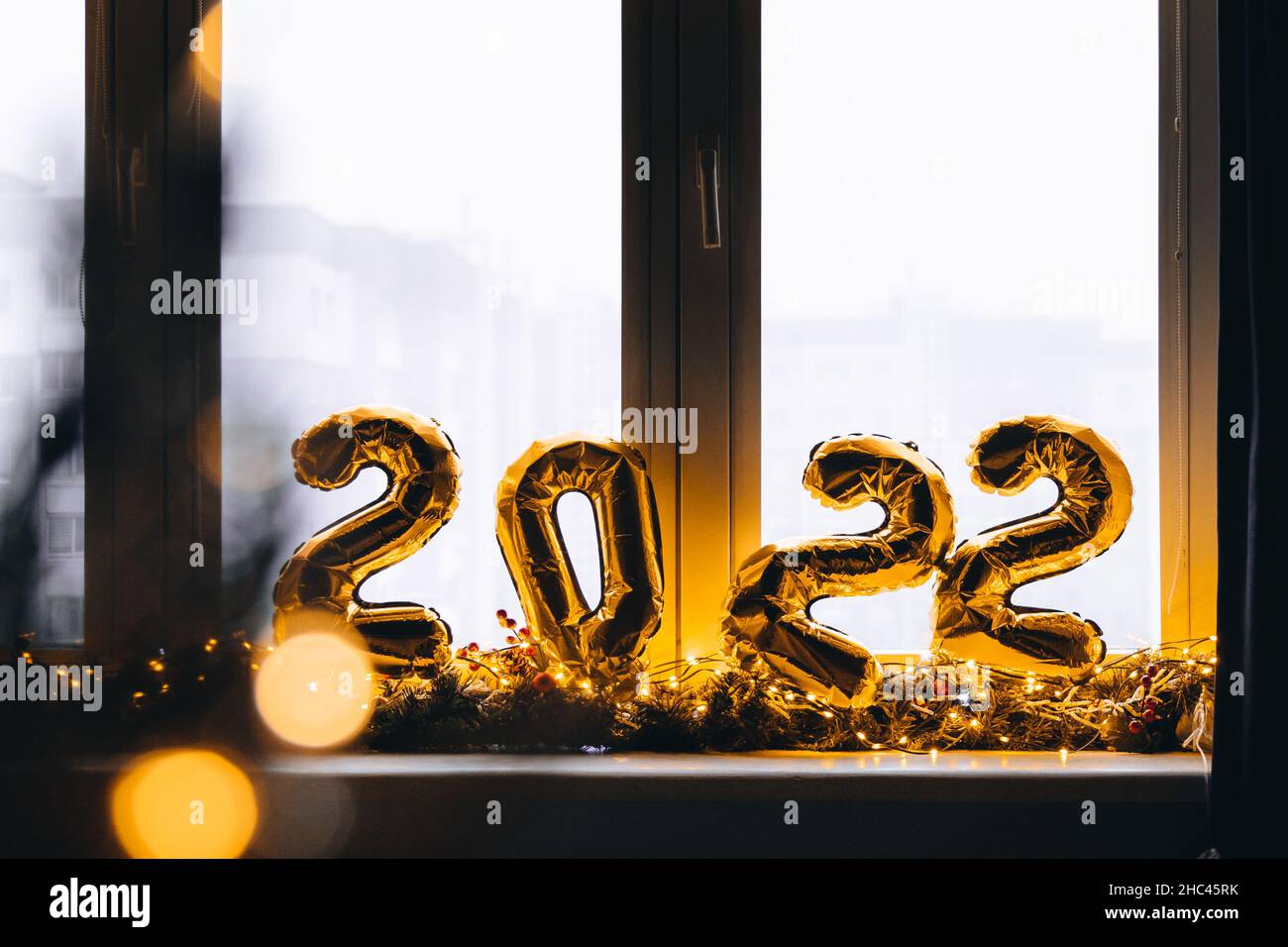 2022 golden foil balloons on blue window sill. Celebrating holidays at home, festive decor concept. Happy New Year 2022. close-up numbers of year 2022 Stock Photo