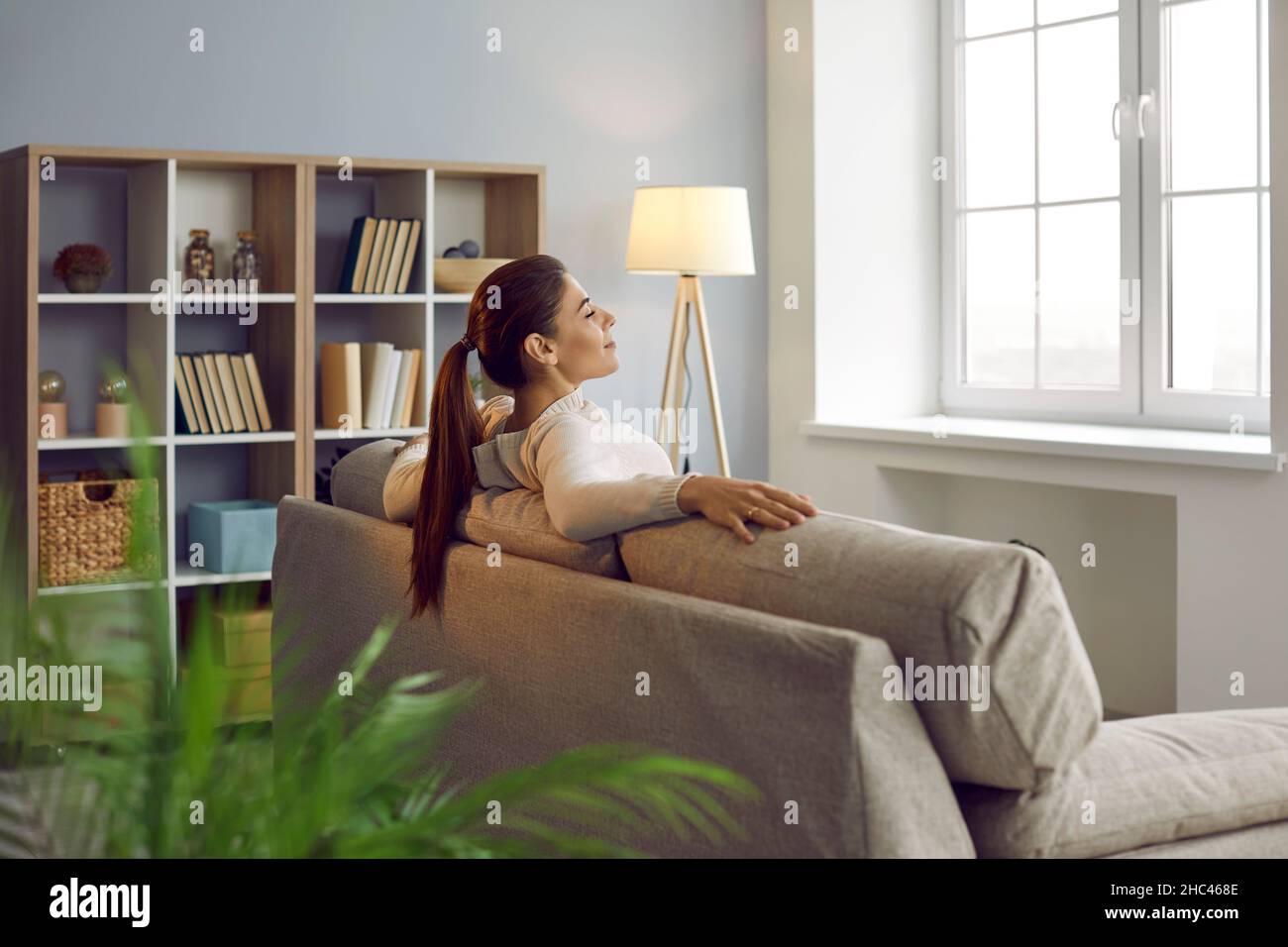 Happy woman enjoying weekend and relaxing on comfortable couch in cozy room at home Stock Photo