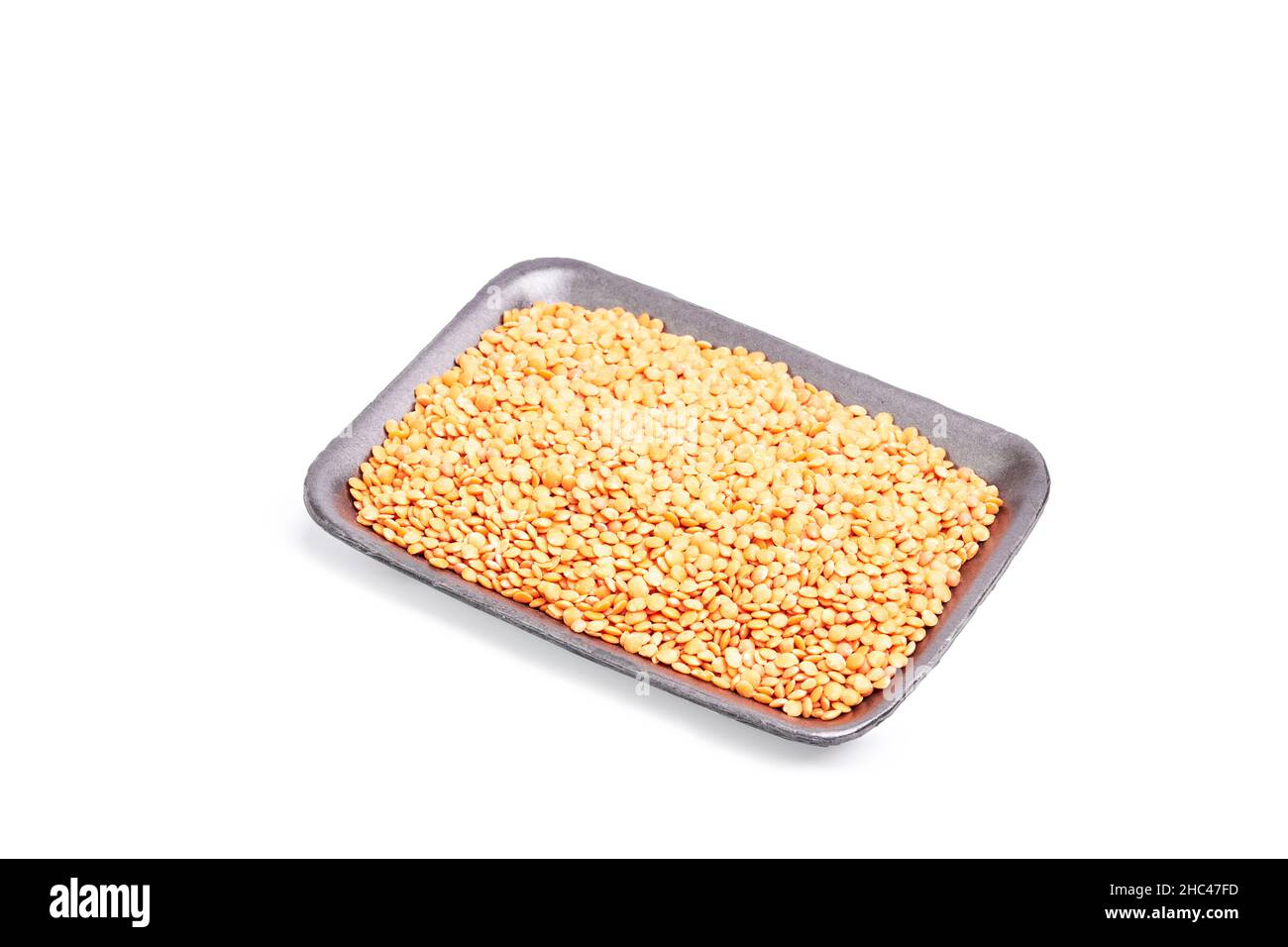 Black tray with raw orange lentils on a white background. Healthy food concept Stock Photo