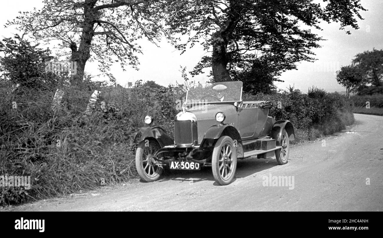 Man driving 1925 drop head coupe open top Bullnose Morris car in country lane, Wales, UK Stock Photo