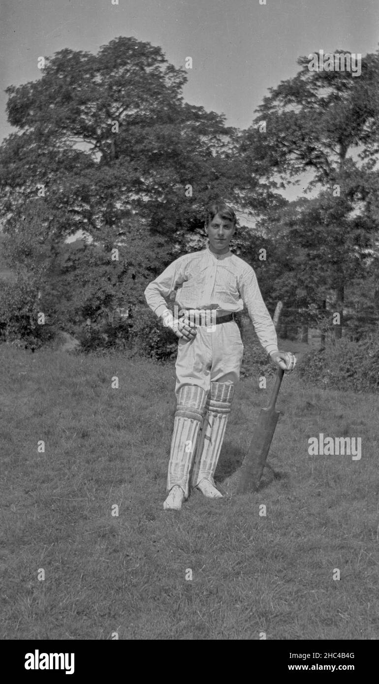 Young man posing for photo in field with cricket bat and pads in traditional dress for cricket a century ago (1916) Stock Photo