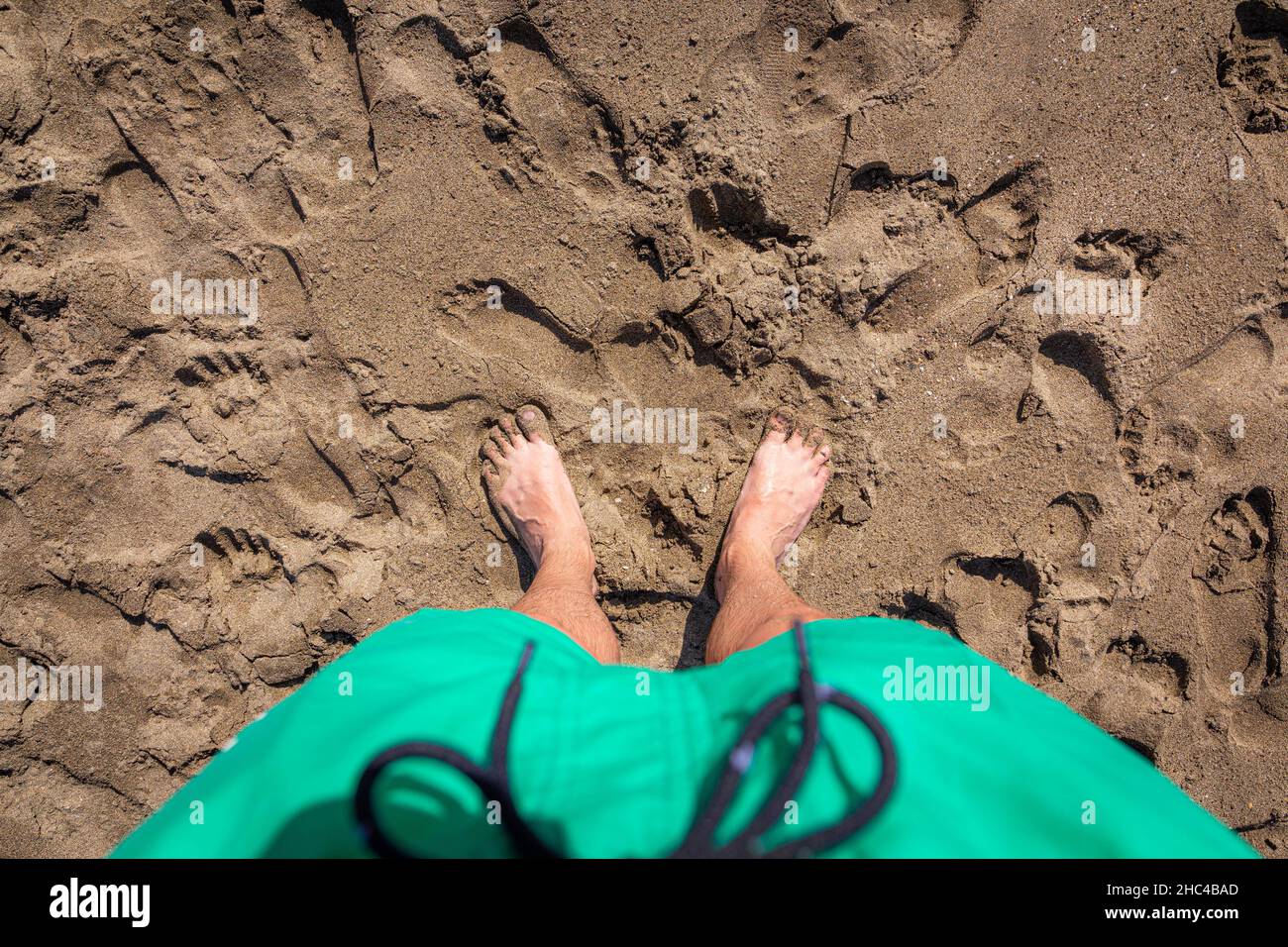 Male feet upon shorts on the beach sand, top view Stock Photo