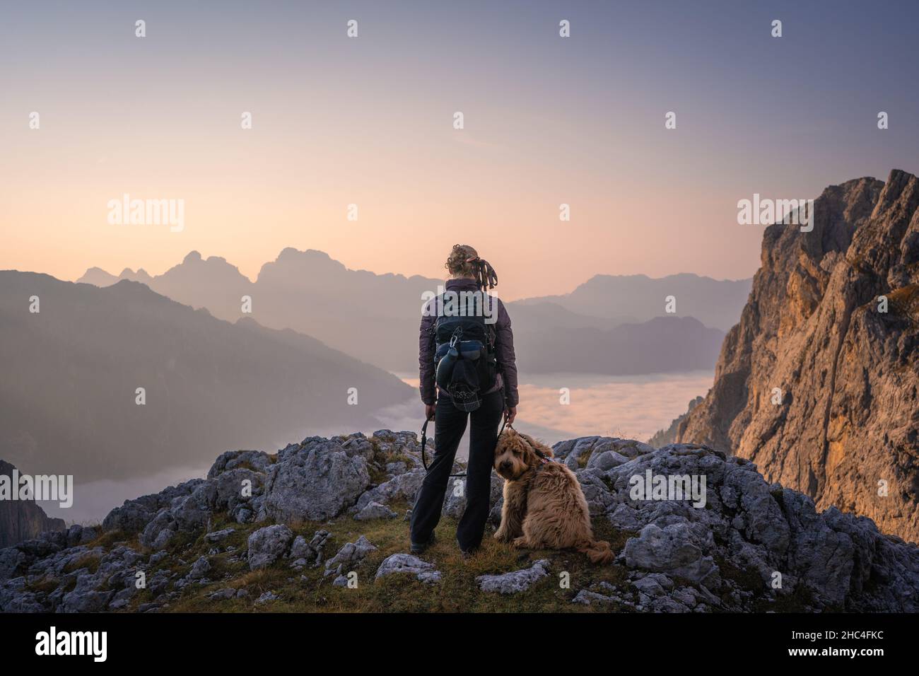 hiker on top of a mountain of pale di san martino in the dolomites enjoying sunrise Stock Photo
