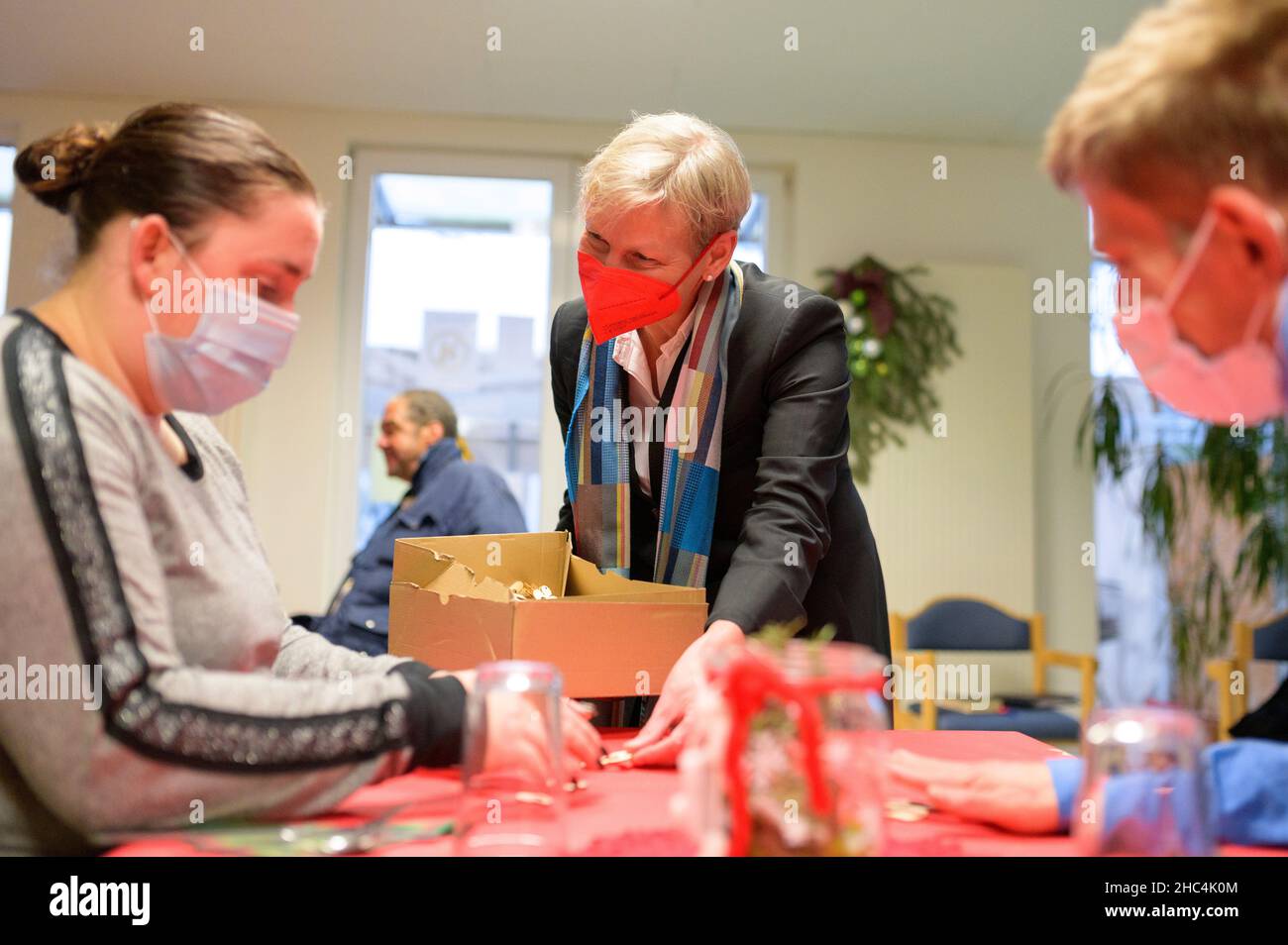 Hamburg, Germany. 24th Dec, 2021. Hamburg's bishop Kirsten Fehrs gives away a small wooden angel to the guests after a service in a facility for homeless people on Christmas Eve and talks to them. Credit: Jonas Walzberg/dpa/Alamy Live News Stock Photo