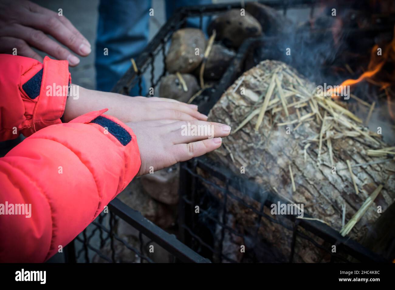 A kid warming hands over a fire during winter Stock Photo