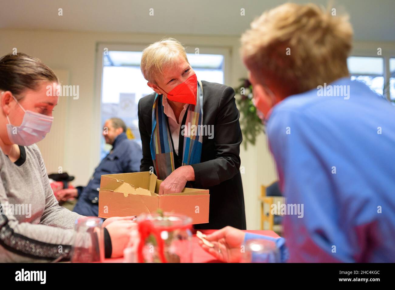Hamburg, Germany. 24th Dec, 2021. Hamburg's bishop Kirsten Fehrs gives away a small wooden angel to the guests after a service in a facility for homeless people on Christmas Eve and talks to them. Credit: Jonas Walzberg/dpa/Alamy Live News Stock Photo