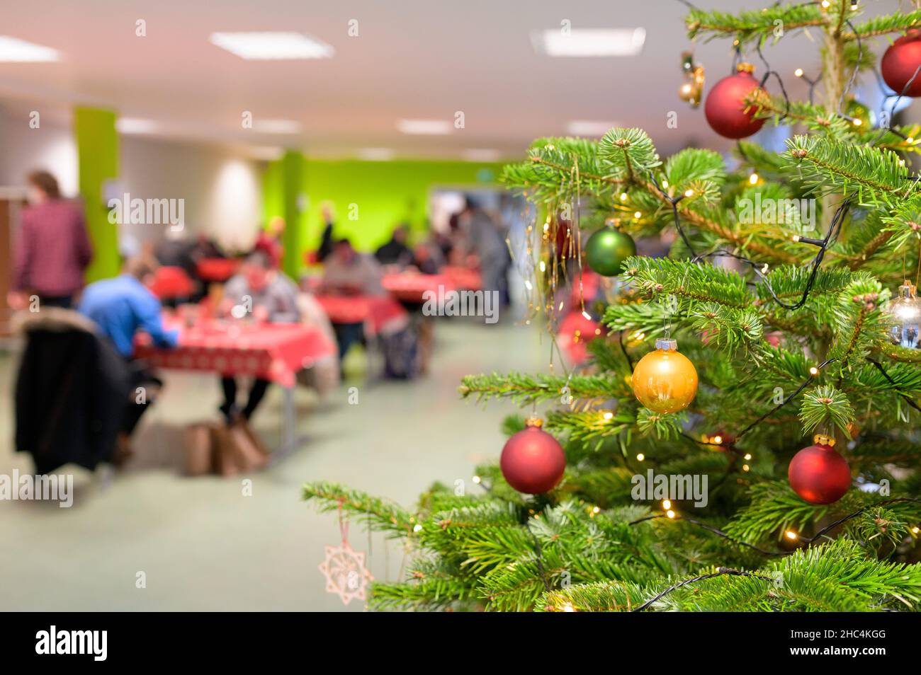 Hamburg, Germany. 24th Dec, 2021. A decorated Christmas tree stands in a small room of a facility for homeless people, while the visitors are eating the Christmas menu. During a devotion in a facility on Christmas Eve, Hamburg's Bishop K. Fehrs read the biblical Christmas story. Credit: Jonas Walzberg/dpa/Alamy Live News Stock Photo