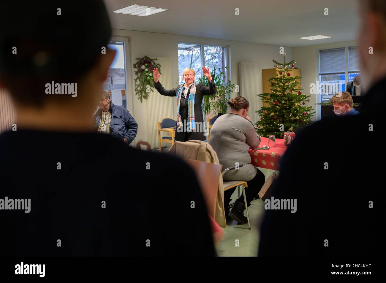 Hamburg, Germany. 24th Dec, 2021. Hamburg's Bishop Kirsten Fehrs (M) blesses those present at a service in a facility for homeless people on Christmas Eve. Credit: Jonas Walzberg/dpa/Alamy Live News Stock Photo