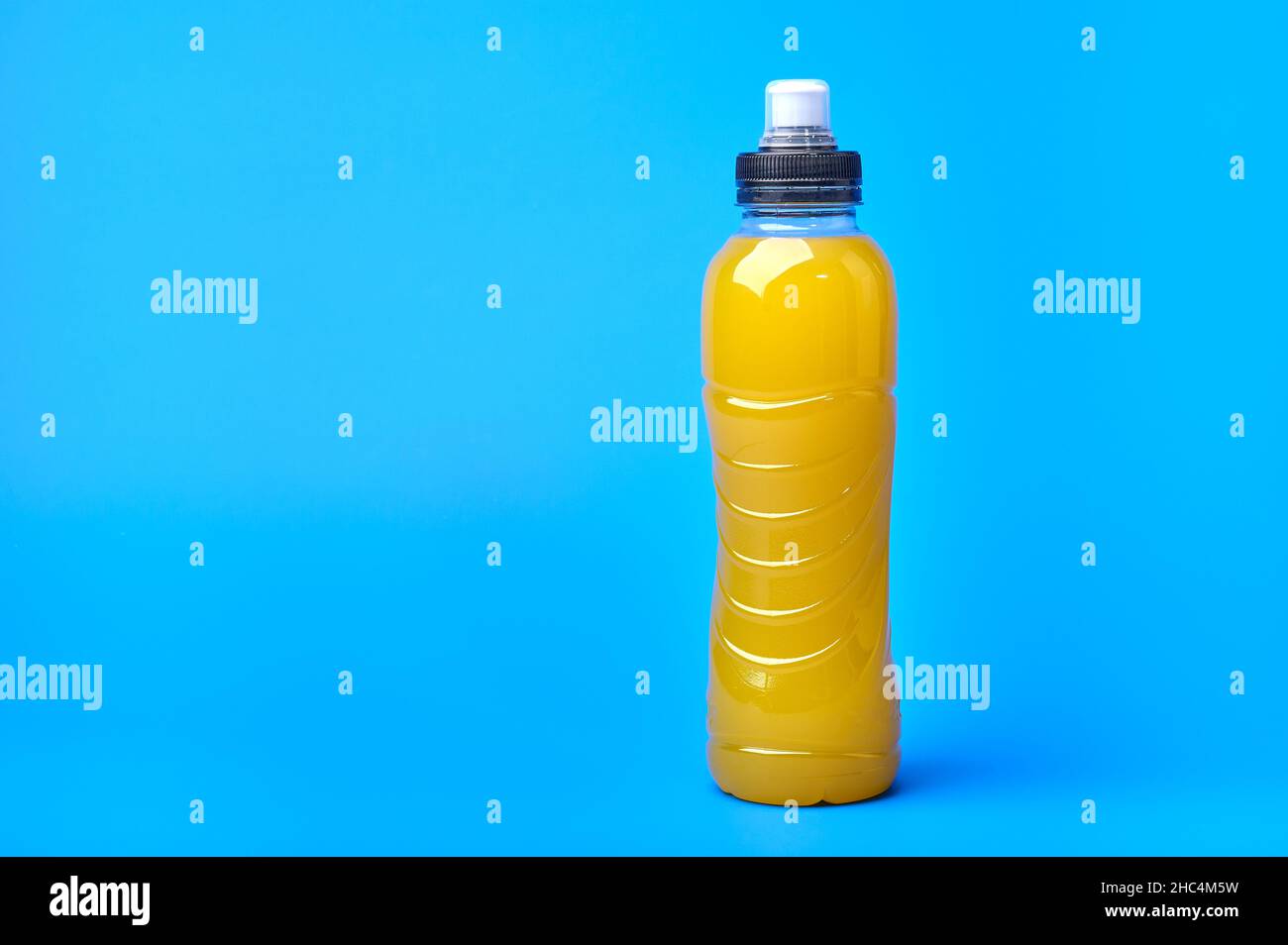 Isotonic energy orange yellow sport drink in plastic bottle on blue