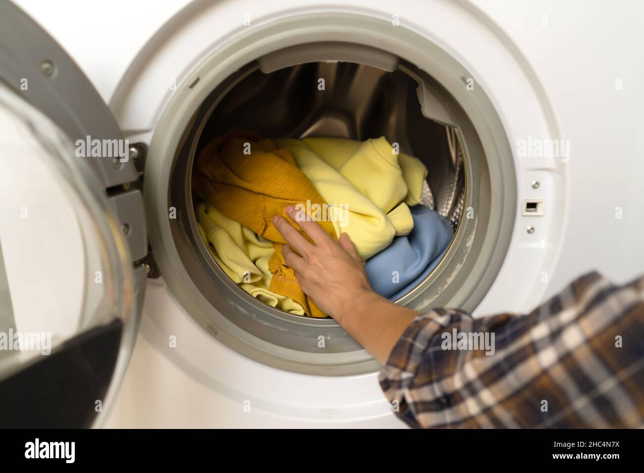 Woman puts bright clothes into a washing machine Stock Photo Alamy