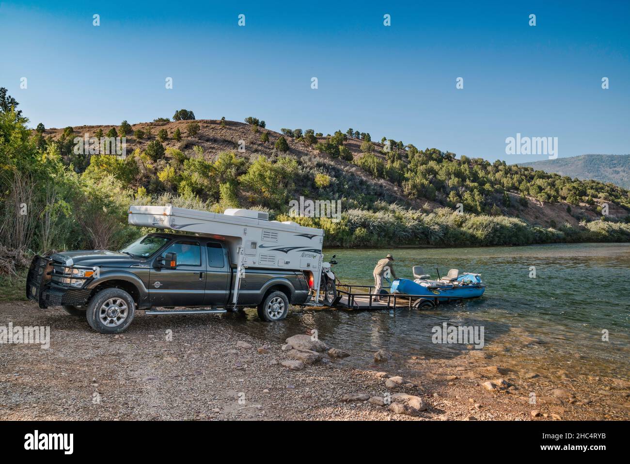 Man unloading pontoon boat, truck camper, Green River at Indian Crossing Boat Ramp and Campground, Browns Park, Utah, USA Stock Photo