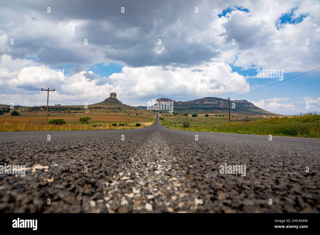 Low angle asphalt tar road in the foreground with a landscape in the Eastern Freestate of South Africa with an empty road and mountains Stock Photo