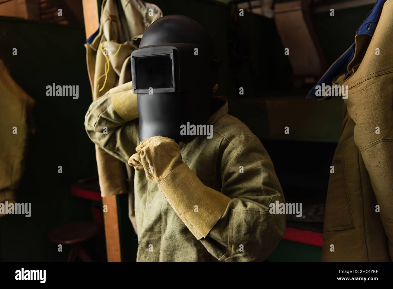 Welder in gloves wearing protective mask with visor in factory Stock Photo