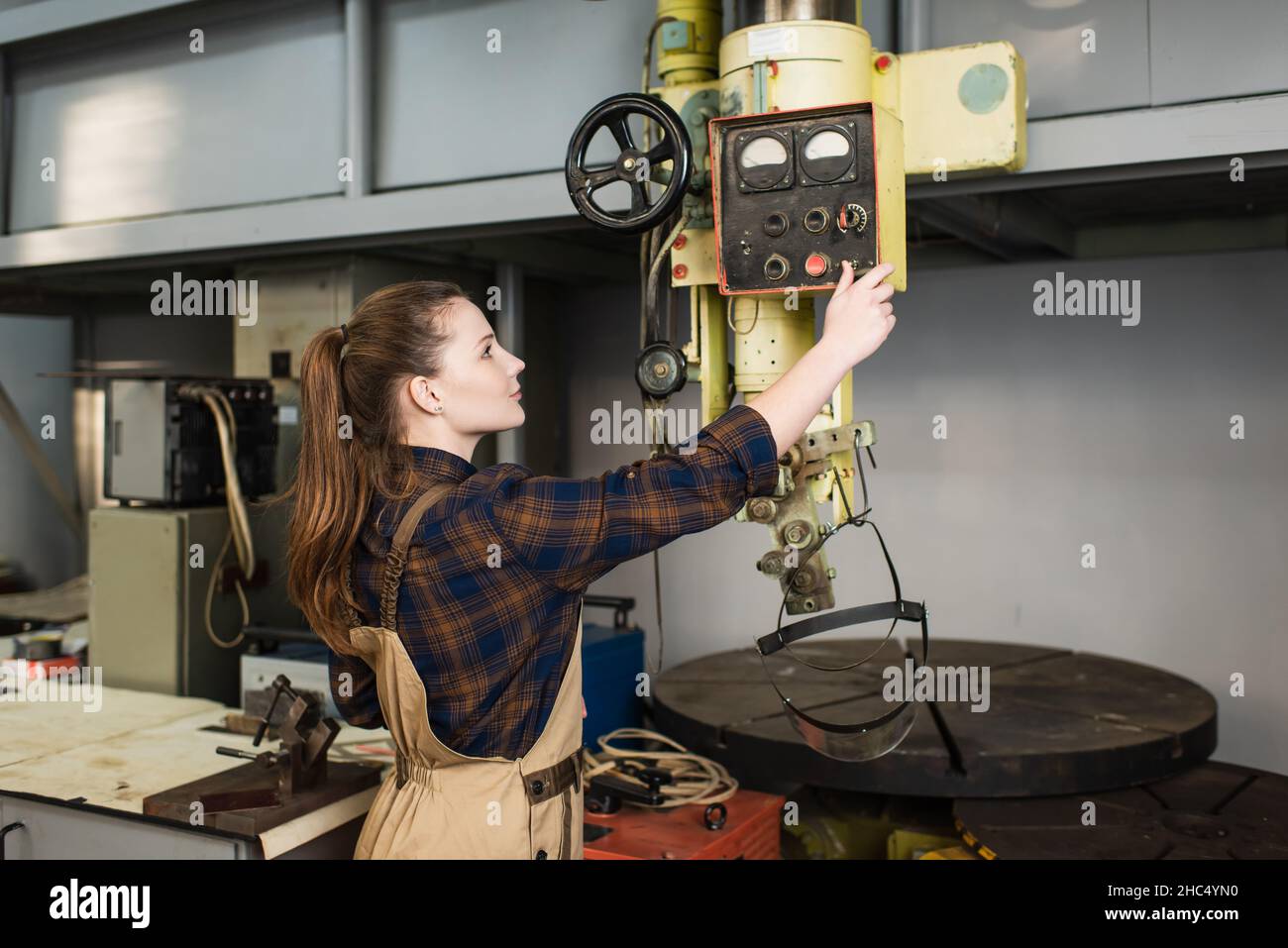 Side view of young welder working with machinery in factory Stock Photo
