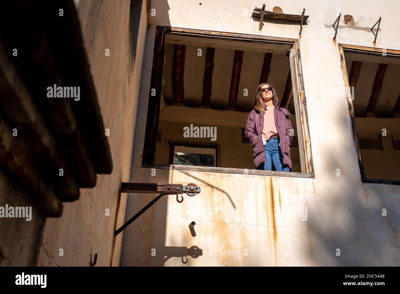 Woman in bra looking out high rise apartment window at dusk stock photo -  OFFSET