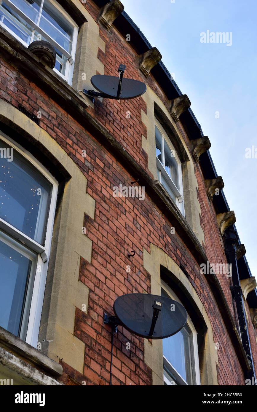 Satellite TV receiving dishes on side of brick house, Stroud, UK Stock Photo