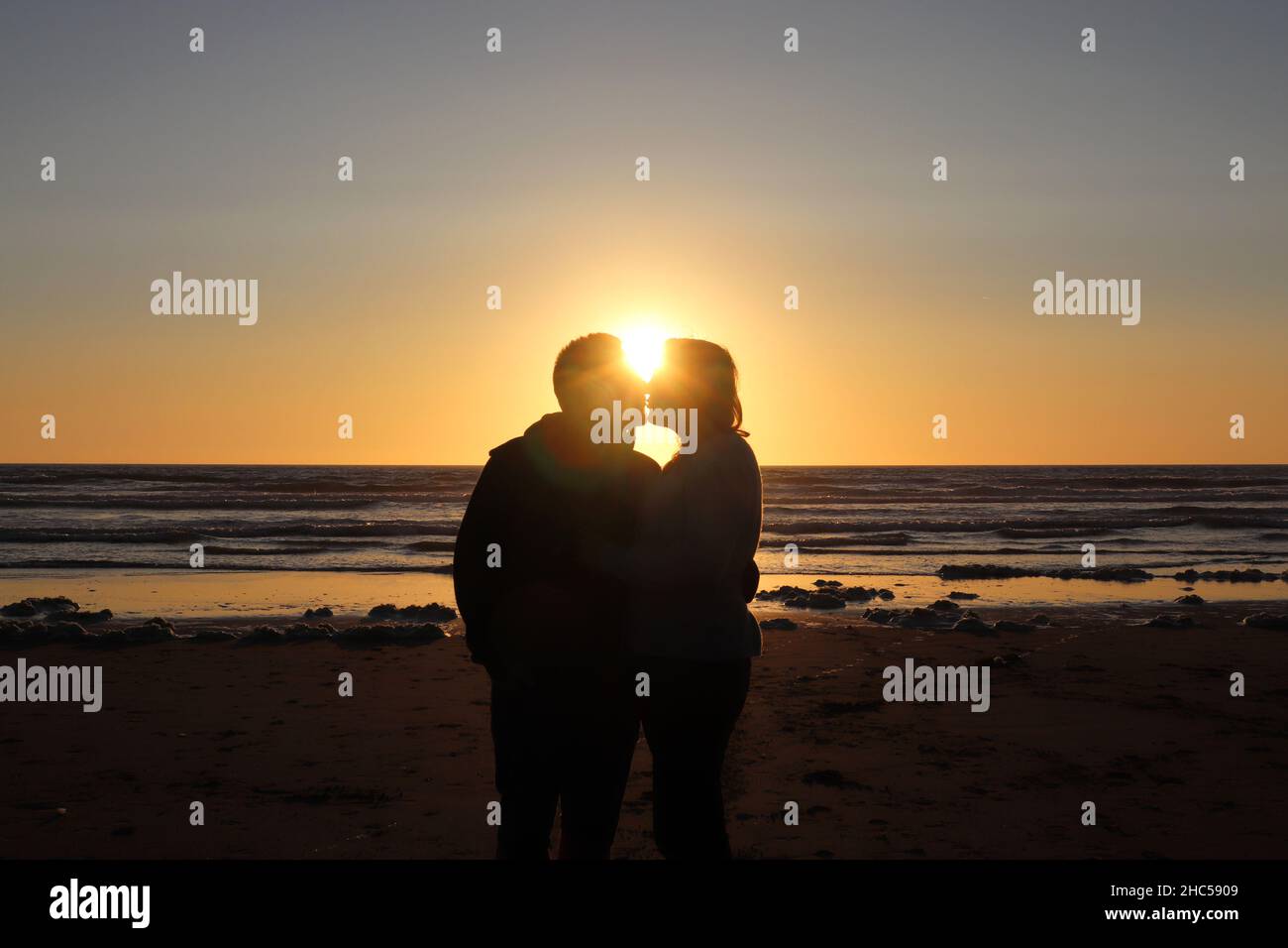 Silhouette of a kissing couple on a beach at sunset Stock Photo - Alamy