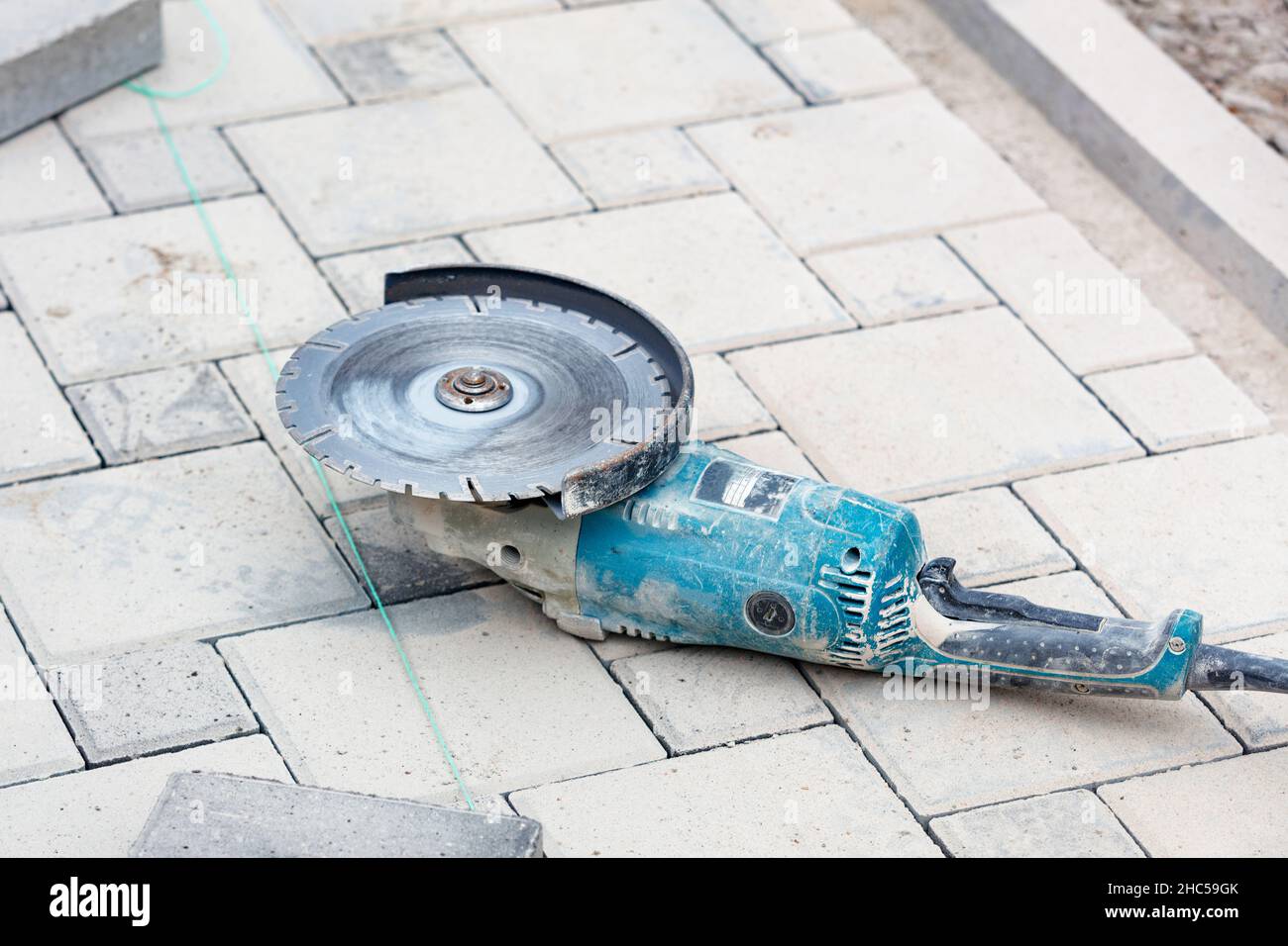 Electric angle grinder with diamond disc for paving slabs. Selective