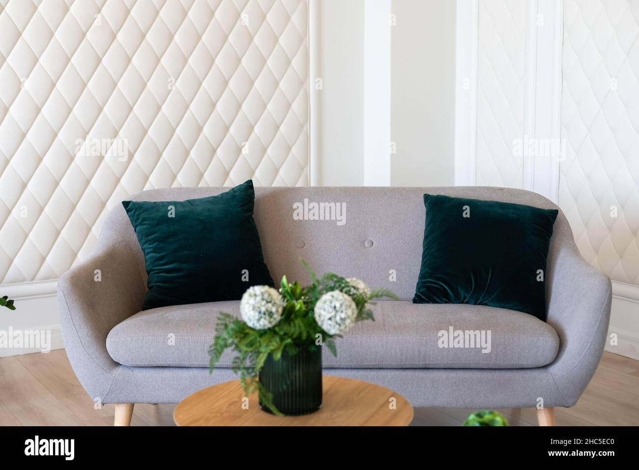 Wooden table and big grey couch with pillows in living room of trendy