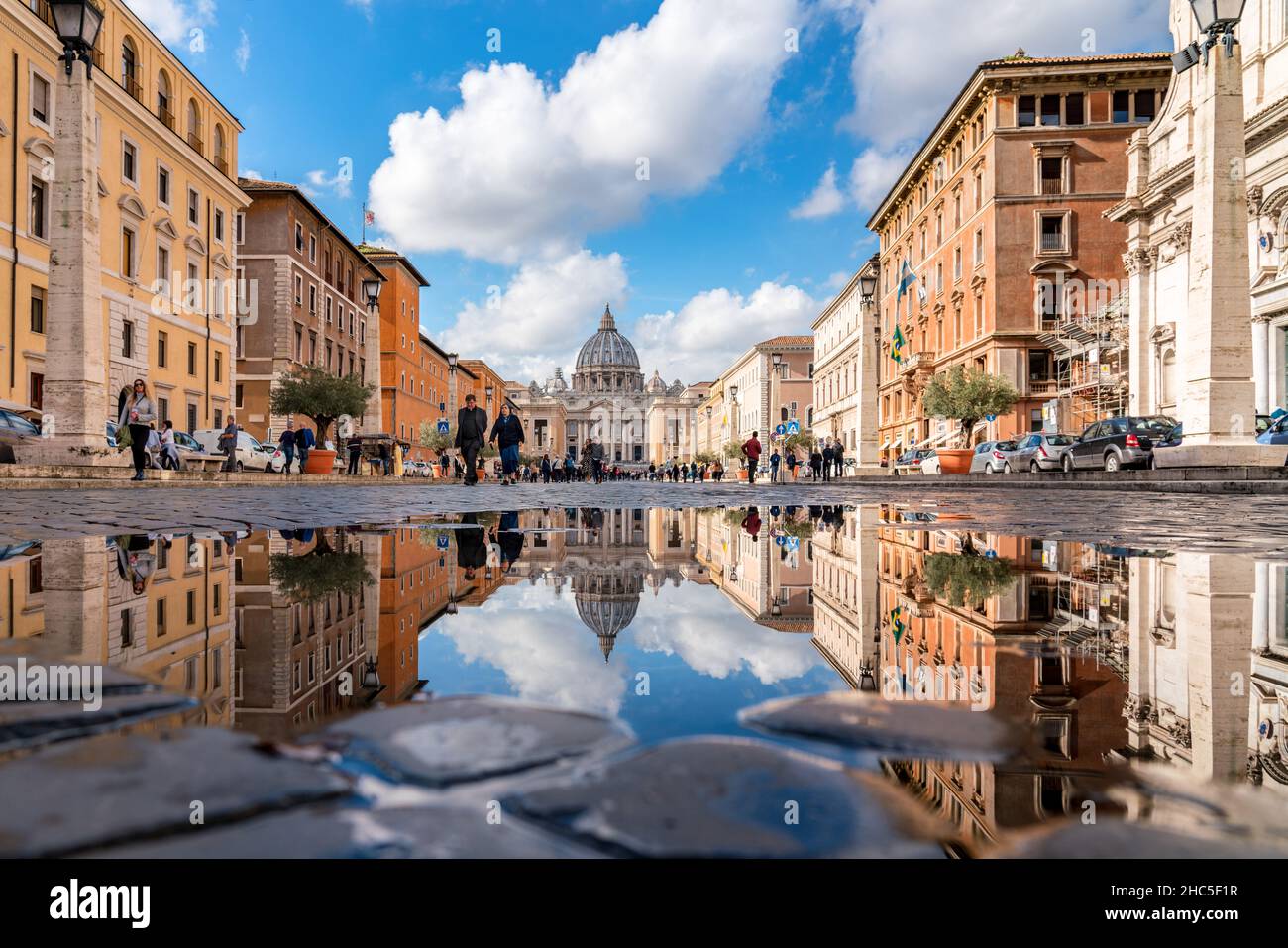 Rome, Italy - November 6, 2018: People walk along the street leading to piazza San Pietro, to the Vatican. The blue sky is reflected in the water Stock Photo