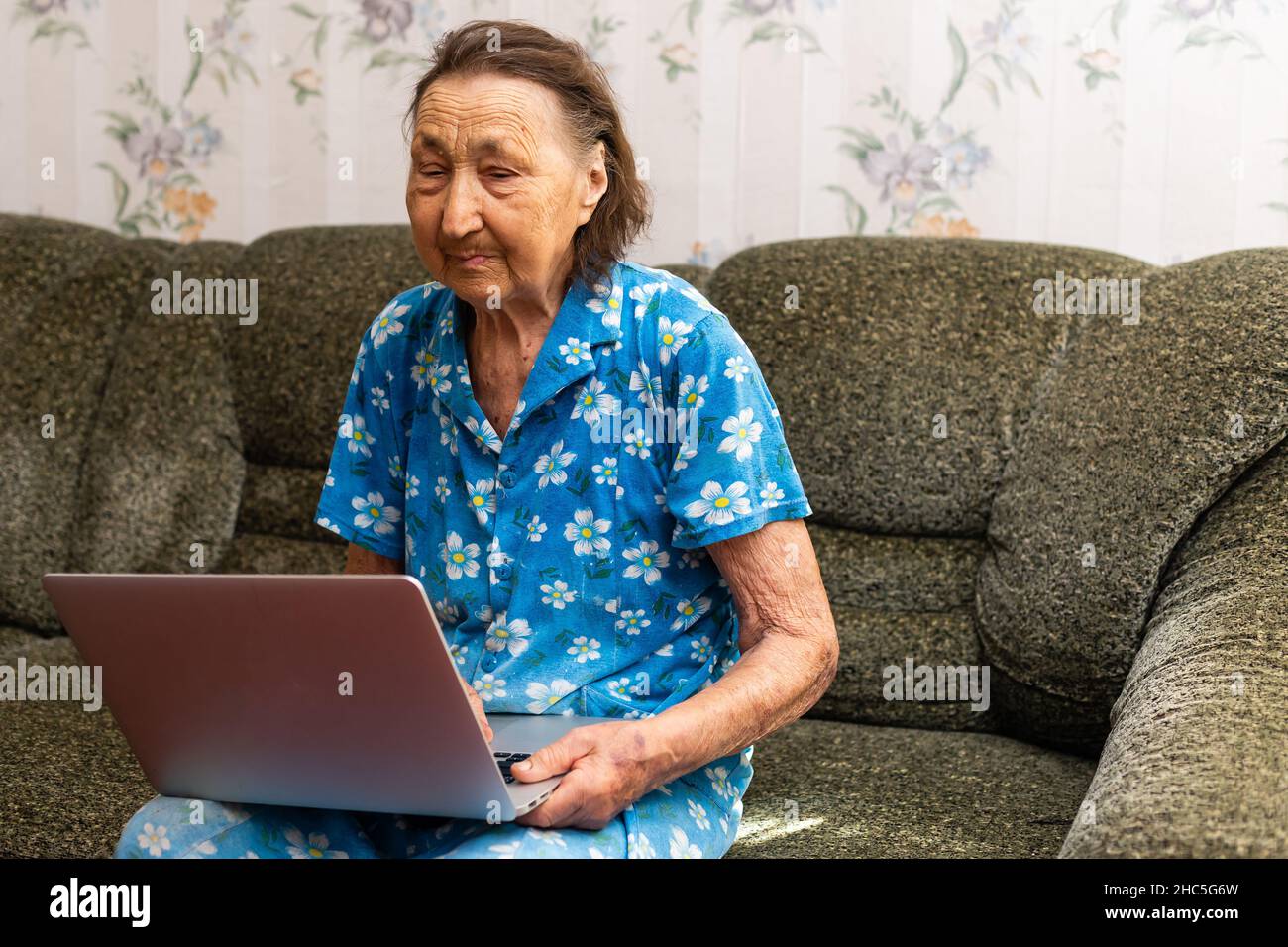 very old woman using laptop sitting in her sofa Stock Photo