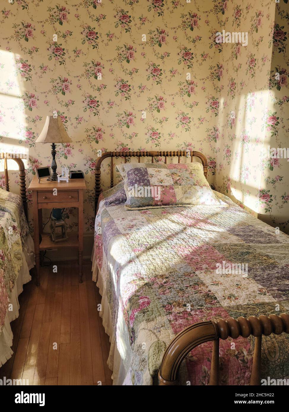 Sunlight window pattern on vintage bed quilt and wallpaper in an old-fashioned bedroom Stock Photo