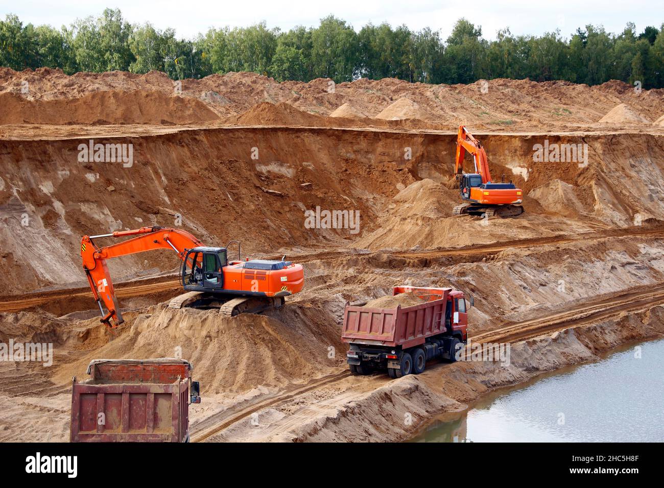 Loading sand into trucks on the sandy career, Mining. Excavators and trucks Stock Photo