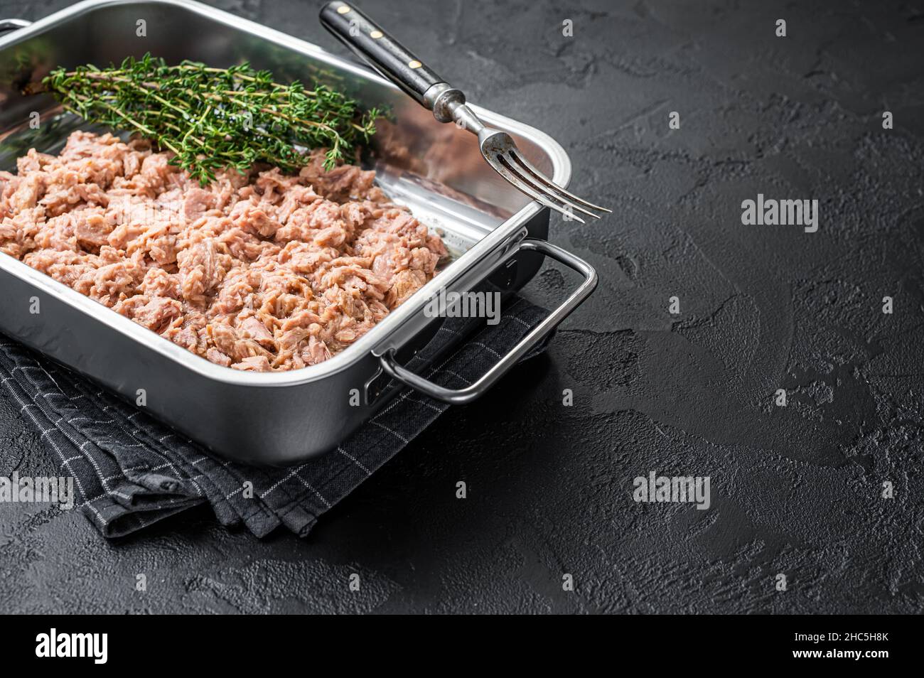 Tuna canned fish with olive oil in a tray . Black background. top view