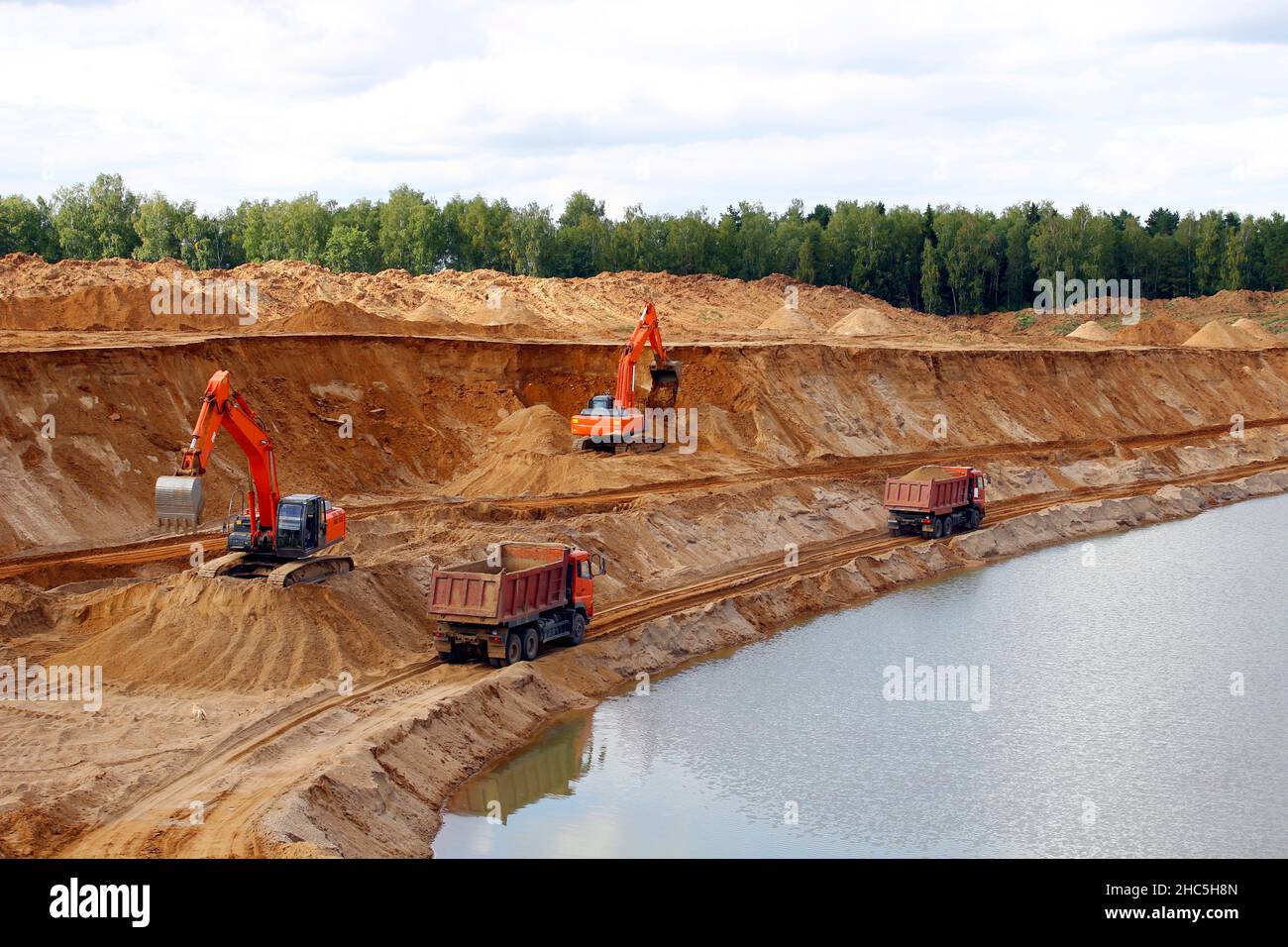 Loading sand into trucks on the sandy career, Mining. Excavators and trucks Stock Photo