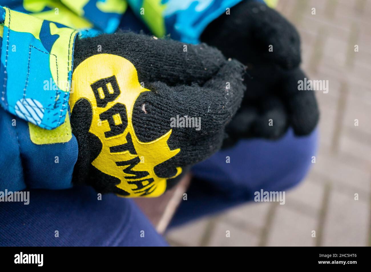 Closeup of a child wearing winter gloves with the Batman superhero on a cold day Stock Photo