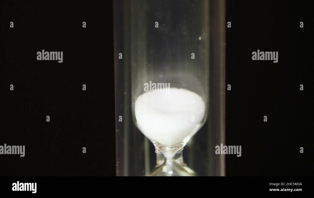 Hourglass. Time Passes - Glass hourglass with white sand on black ...