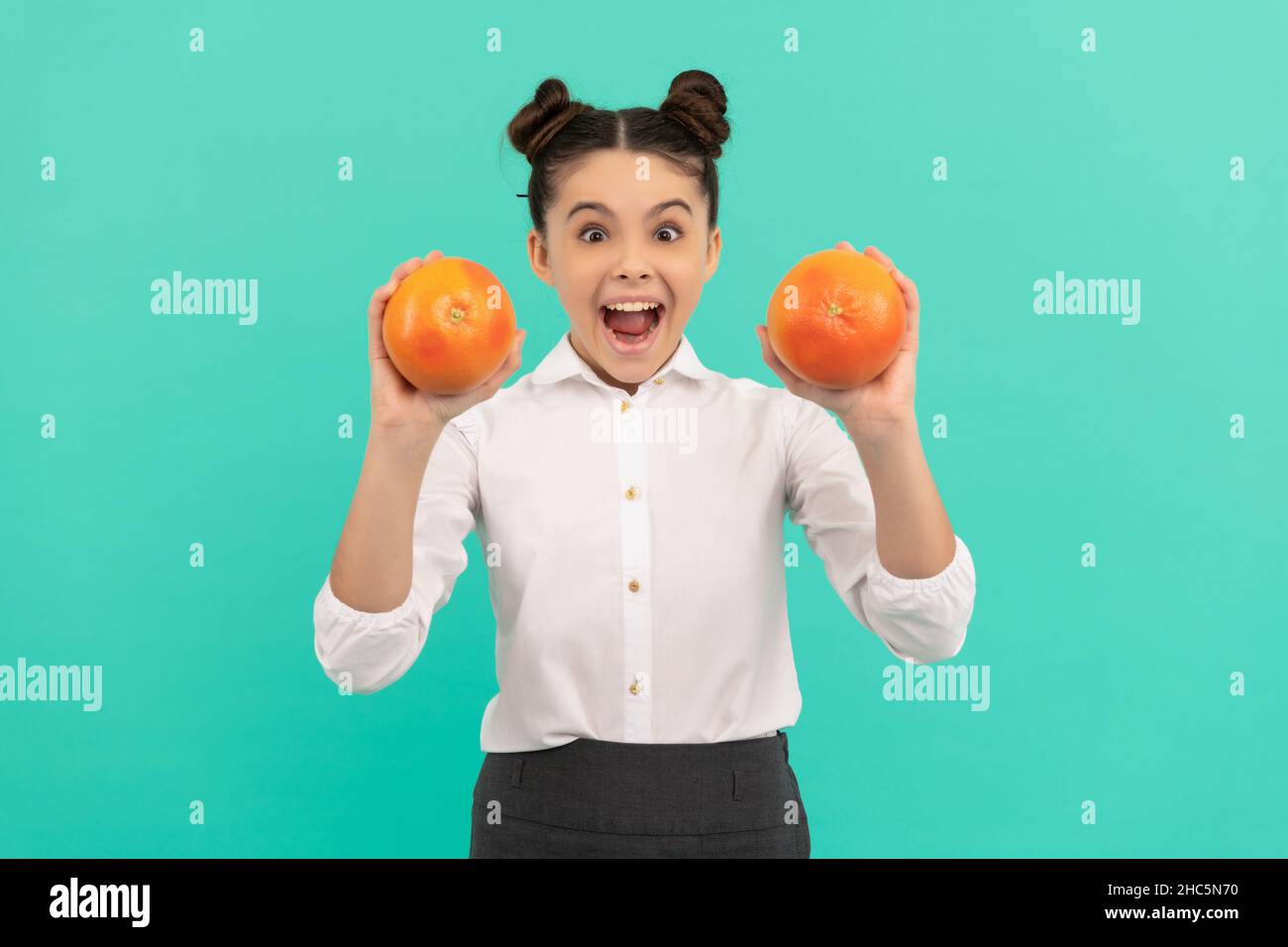 cheerful teen girl wear uniform holding grapefruit on blue background, vitamin Stock Photo