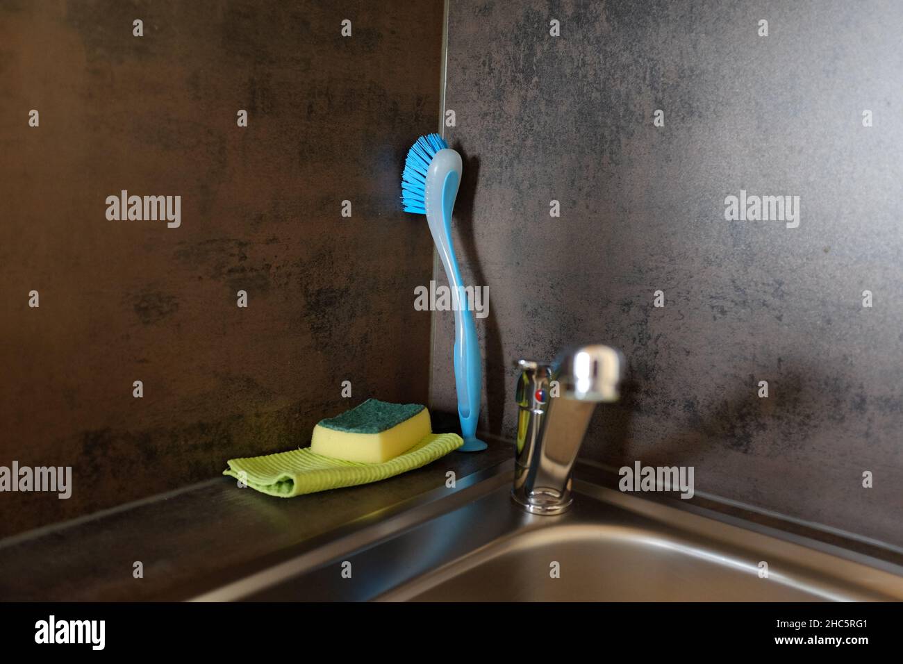 Closeup of a kitchen sink with cleaning materials behind it on the wall Stock Photo