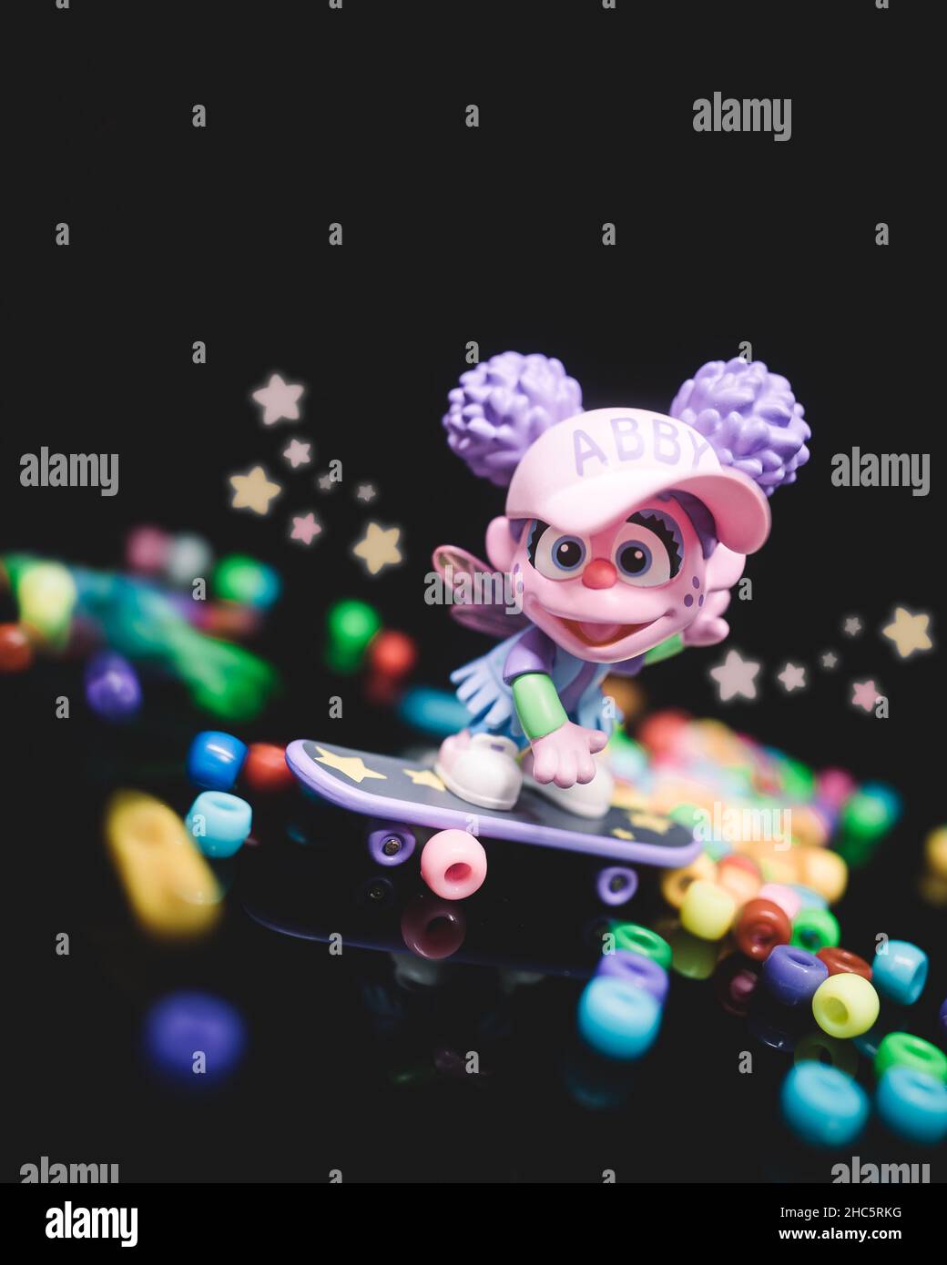 A vertical shot of a toy of Abby from Sesame Street riding a skateboard on a black background Stock Photo