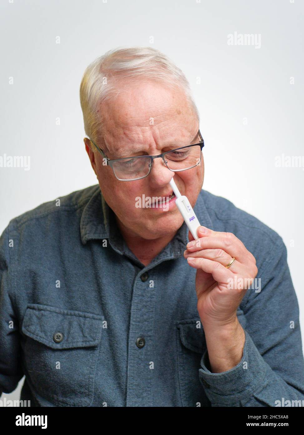 Man swabbing nostril with COVID-19 home antigen test kit. Stock Photo