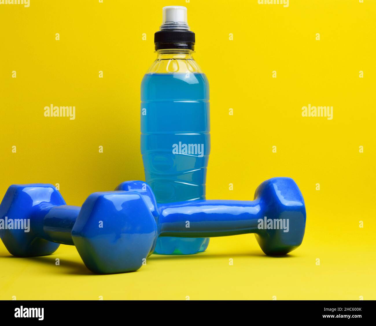 Closeup shot of dumbbells and an energizing drink on a yellow background Stock Photo