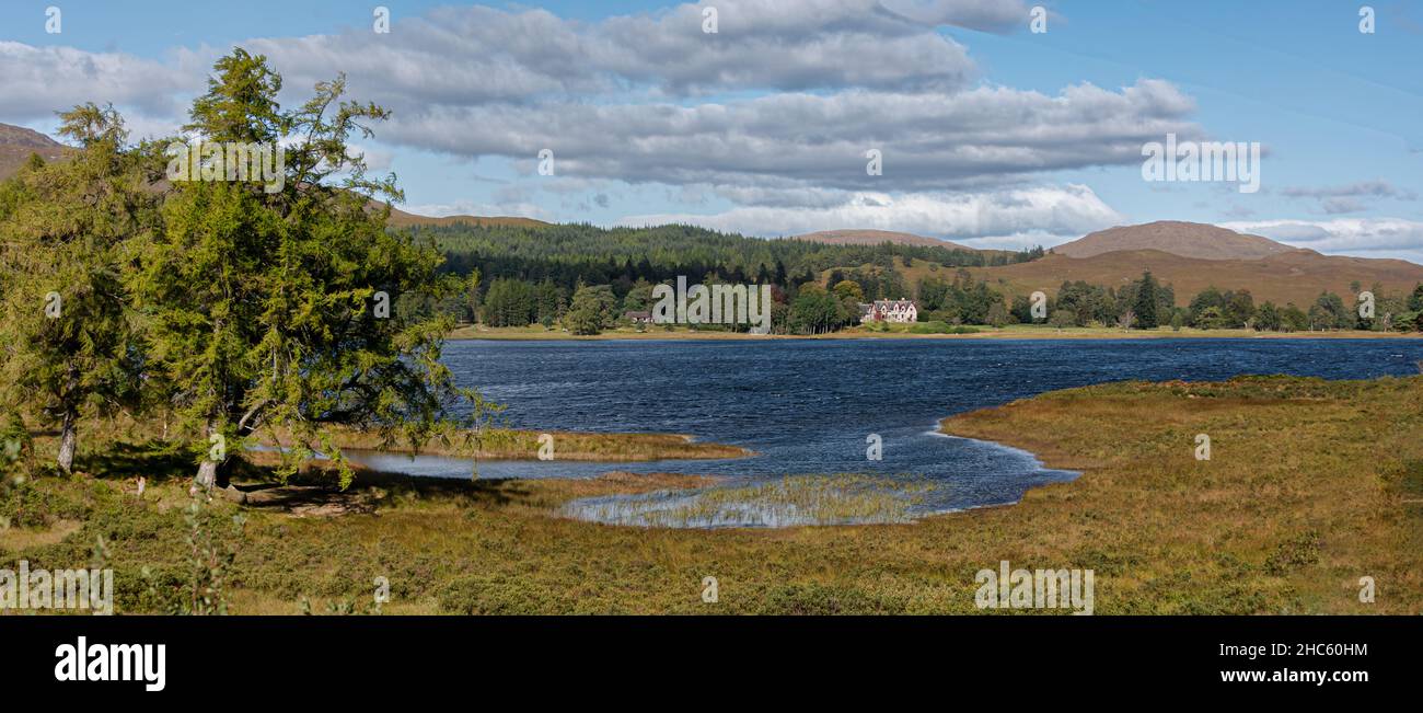 A panoramic landscape view of a large house in the distance on the other side of the lake Stock Photo