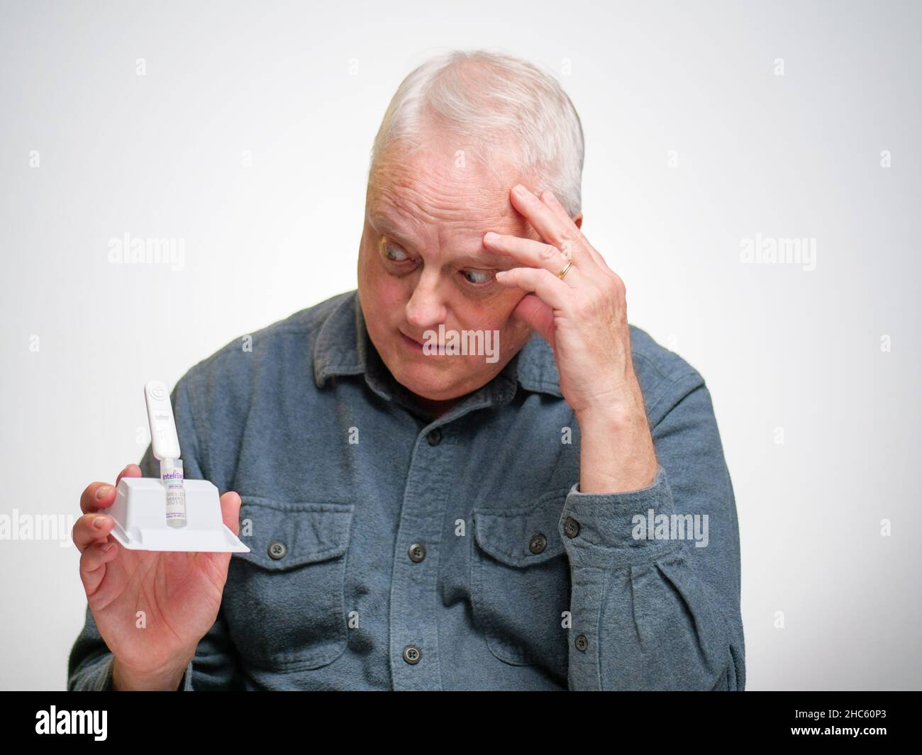 Man with completed home COVID-19 antigen test, concerned look on face. Stock Photo