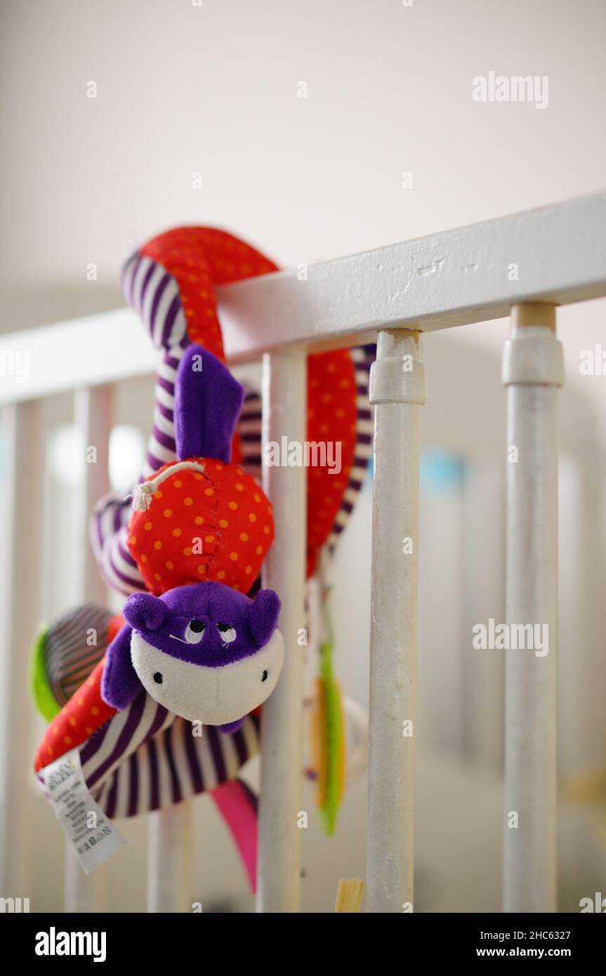 Snake shaped colorful plush toy hanging on a baby bed Stock Photo